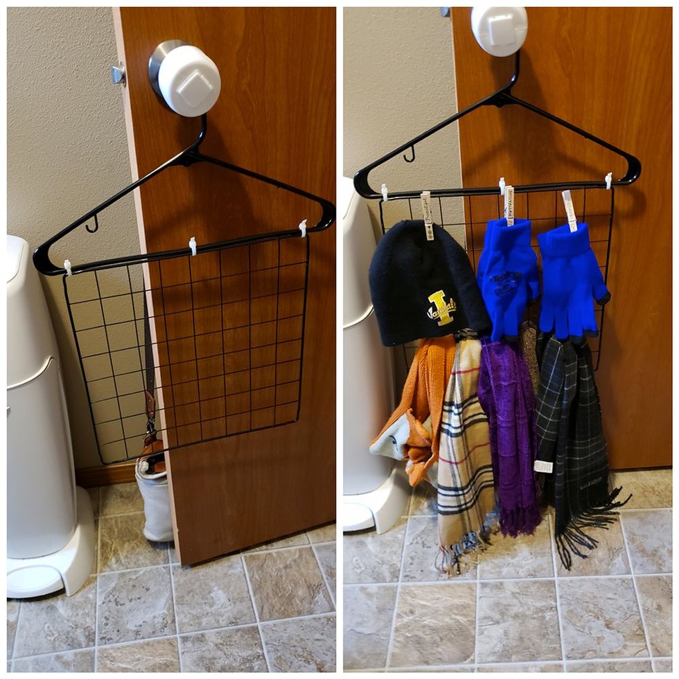 A clothes hanger hangs from a doorknob. Tip tied to it is a square metal grid. Scarves, hats, and mittens hang from it or are clothespinned to it.