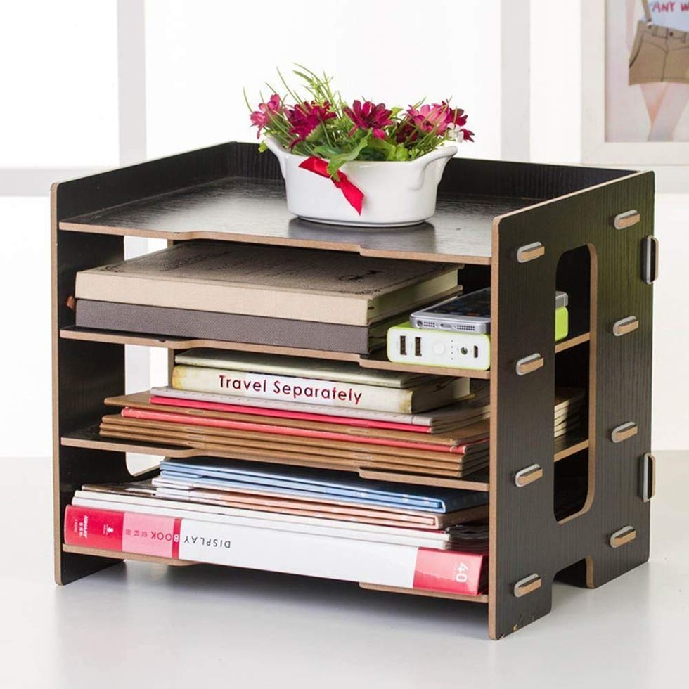 A file organizer with books and a phone piled into each slot.