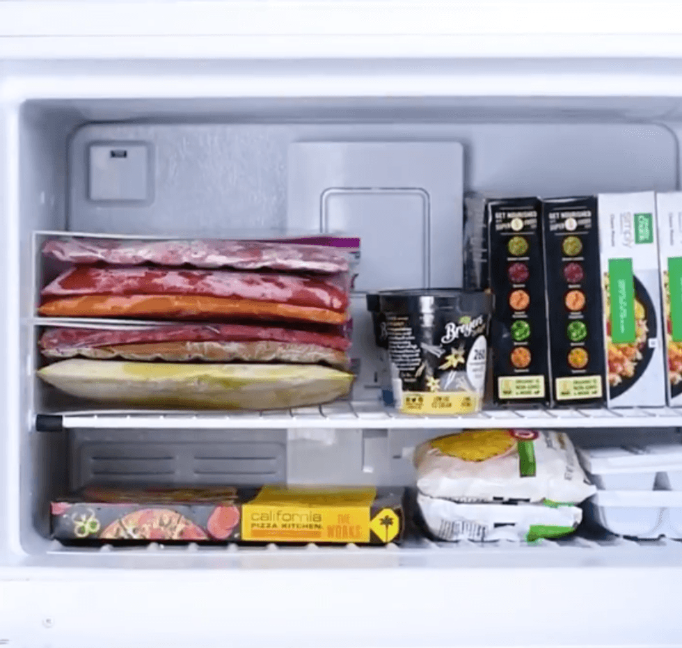 A neat and organized freezer. Magazine holders sit on their sides with flat bags of soup inside.