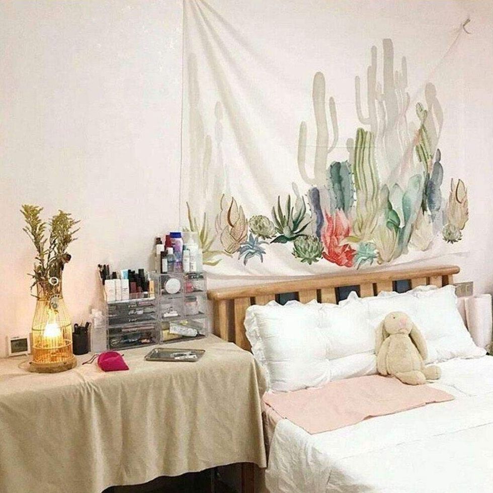 A wall hanging with a desert scene hanging above a bed.
