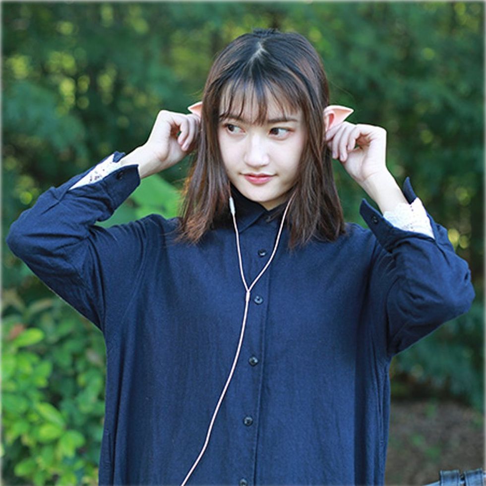 A woman wears fake elf ear earbuds.