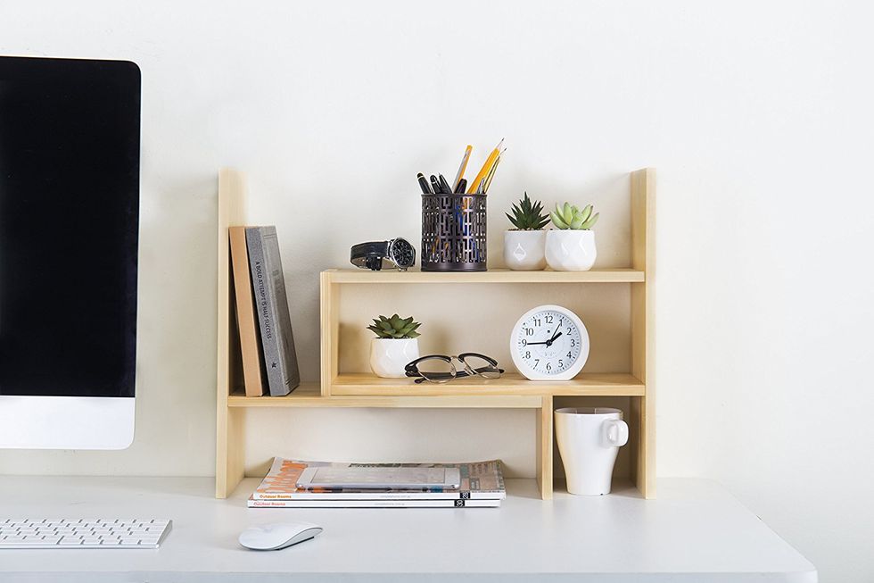 An adjustable desk organizer full of various office items.