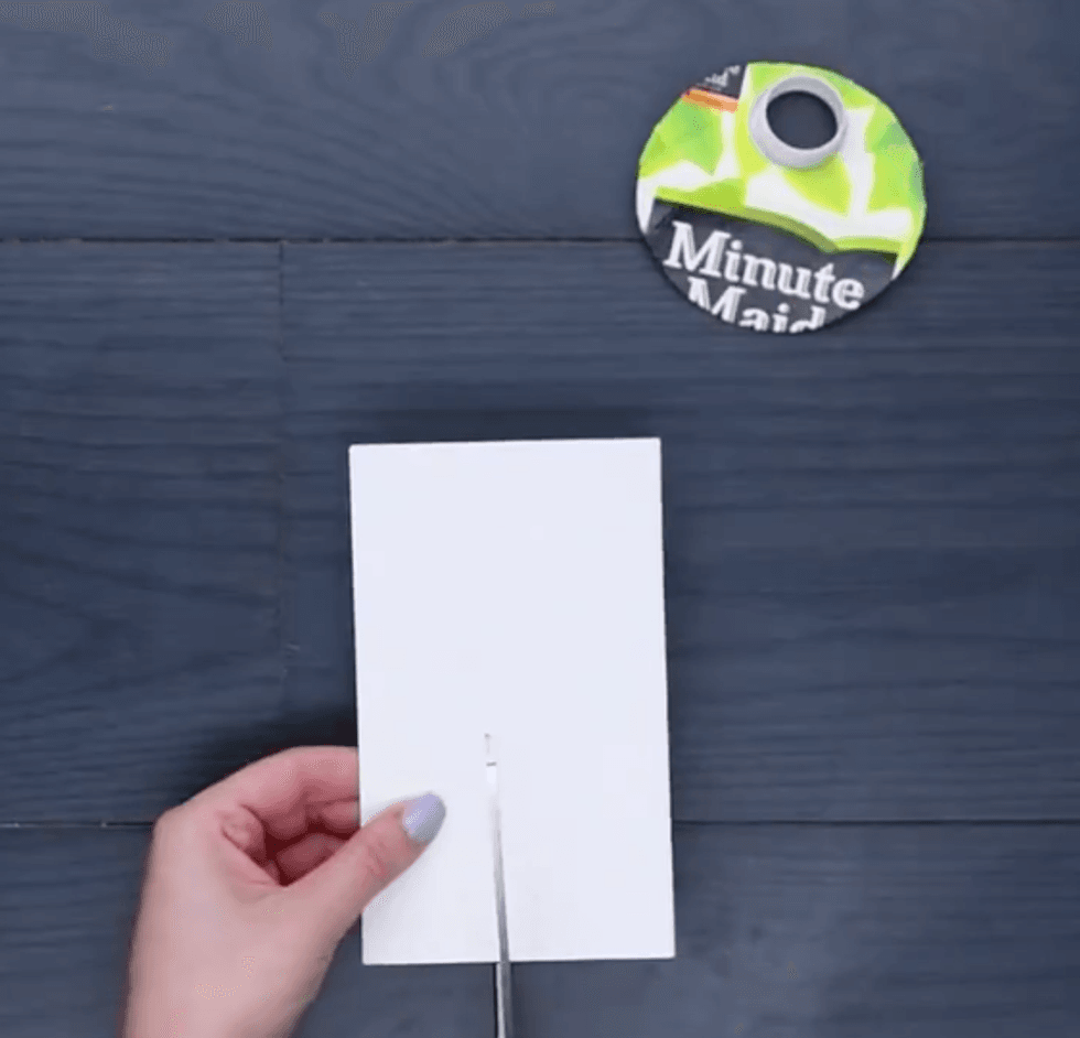Hands hold cardboard and cut it with scissors