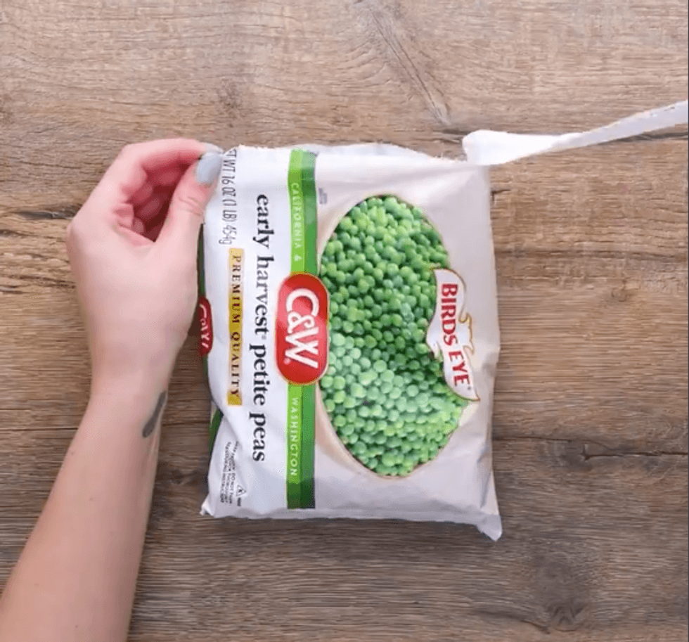 Hands opening a bag of frozen peas
