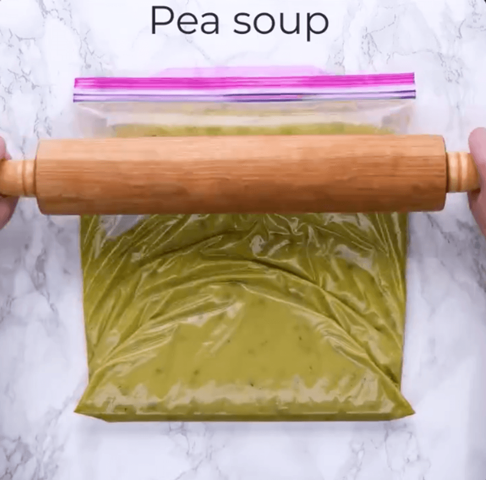 Someone uses a rolling pin on a bag of pea soup