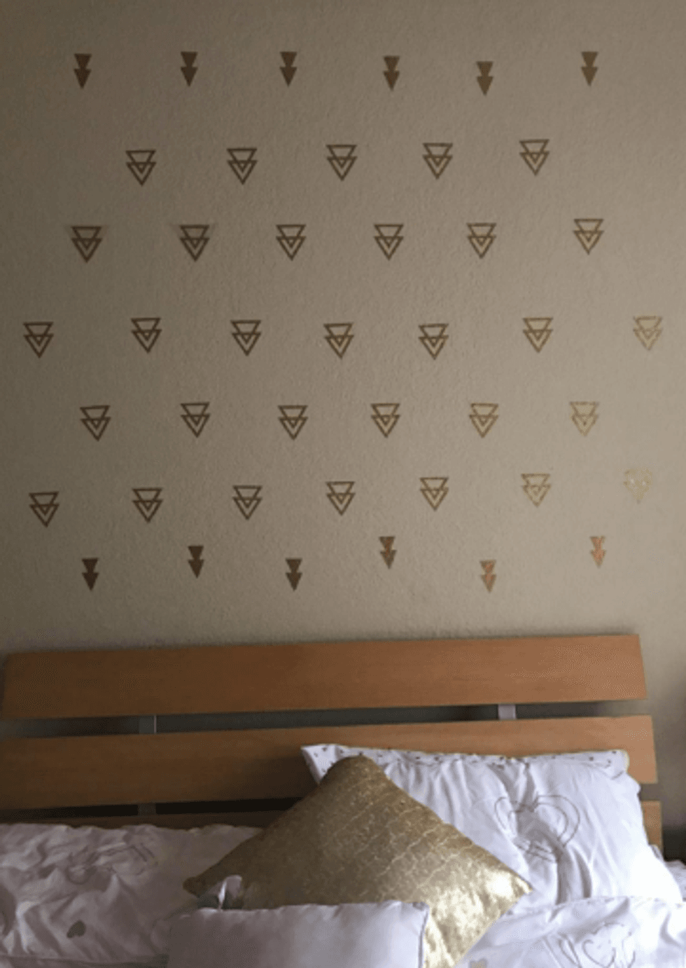 Triangle wall decals on a wall above a bedroom.